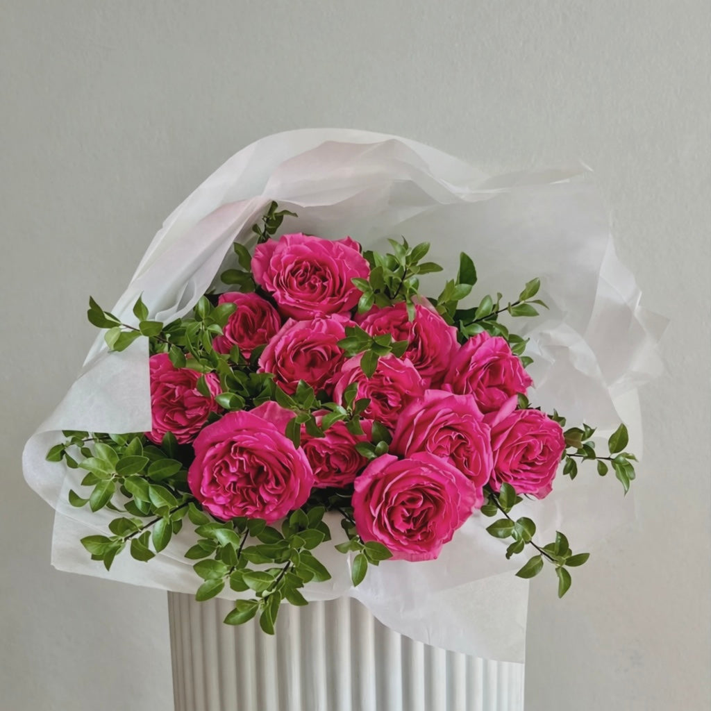 Bouquet of pink roses with green leaves wrapped in paper for Valentine's Day